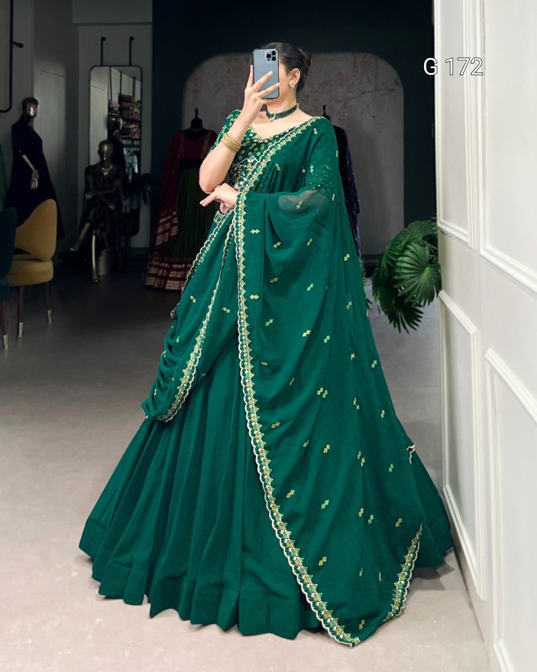 Person wearing a green saree with gold embroidery in a room setting.
