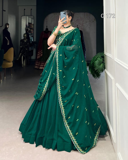 Person wearing a green saree with gold embroidery in a room setting.