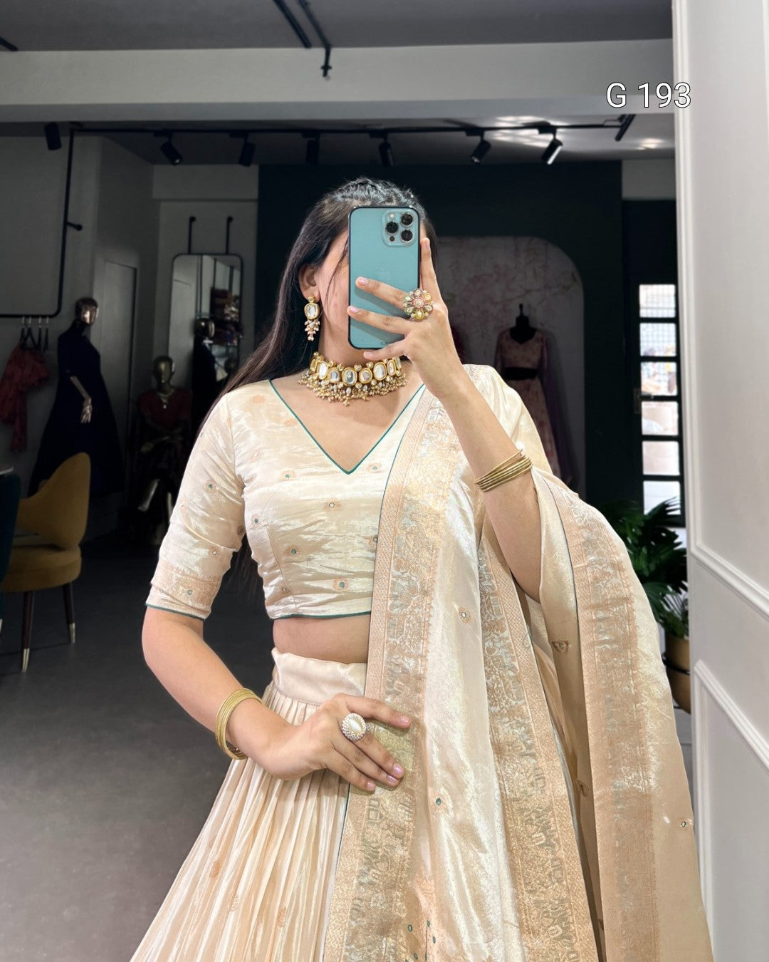 Woman taking a mirror selfie wearing a traditional outfit with jewelry.