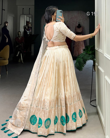 Woman in a traditional outfit with a long skirt and open back, standing in a room with mirrors and clothing.