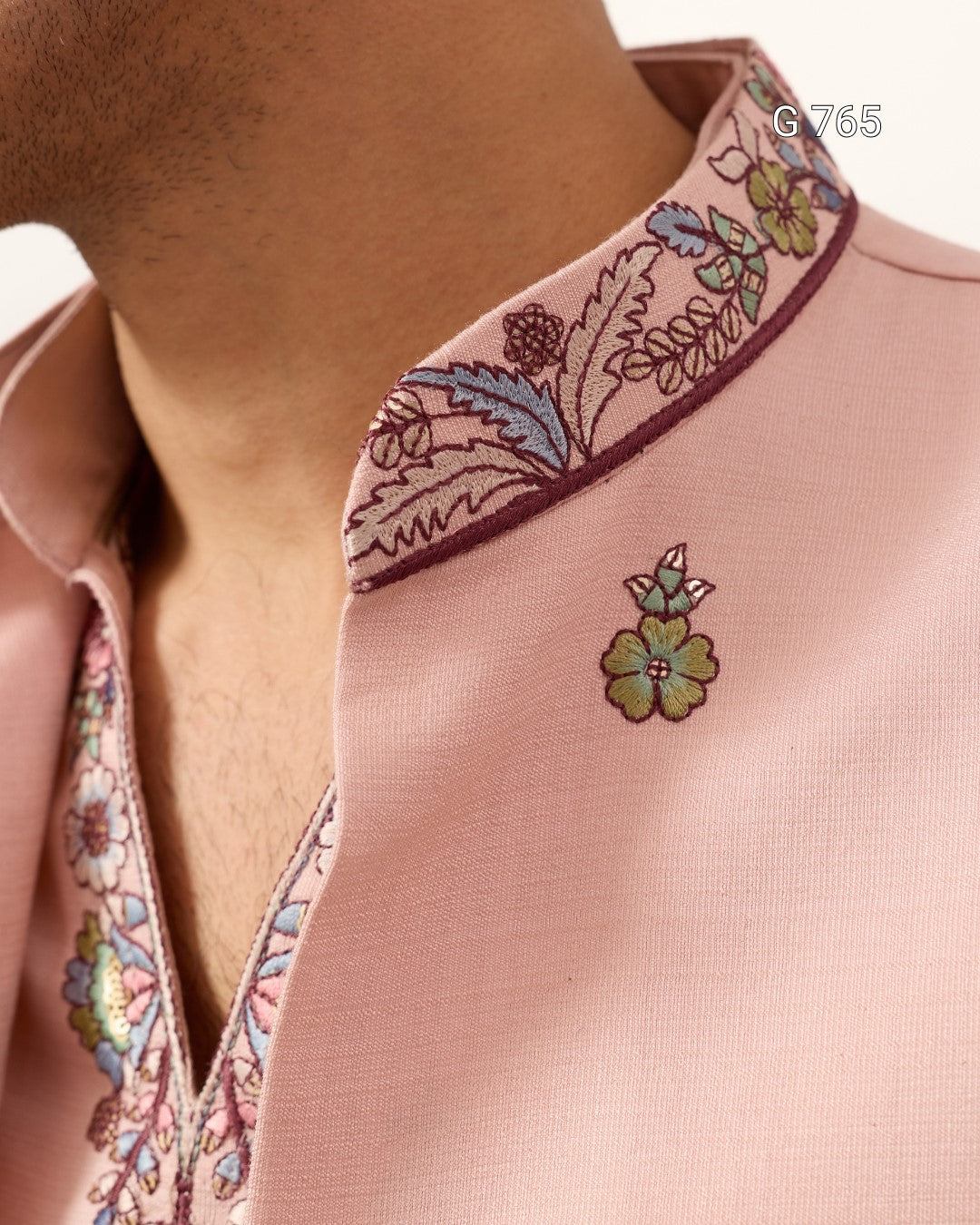 Close-up of a pink garment with floral embroidery on a plain background