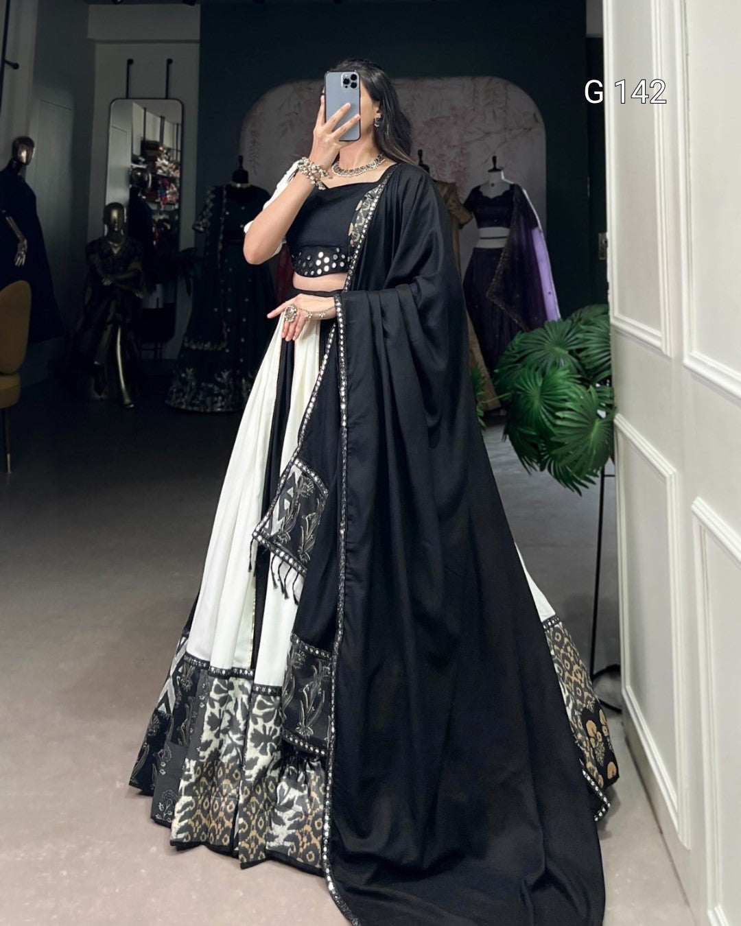 Person wearing a black and white traditional outfit with a saree in a room.