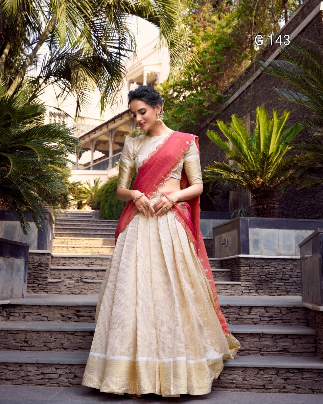 Woman in a traditional saree standing outdoors with greenery in the background