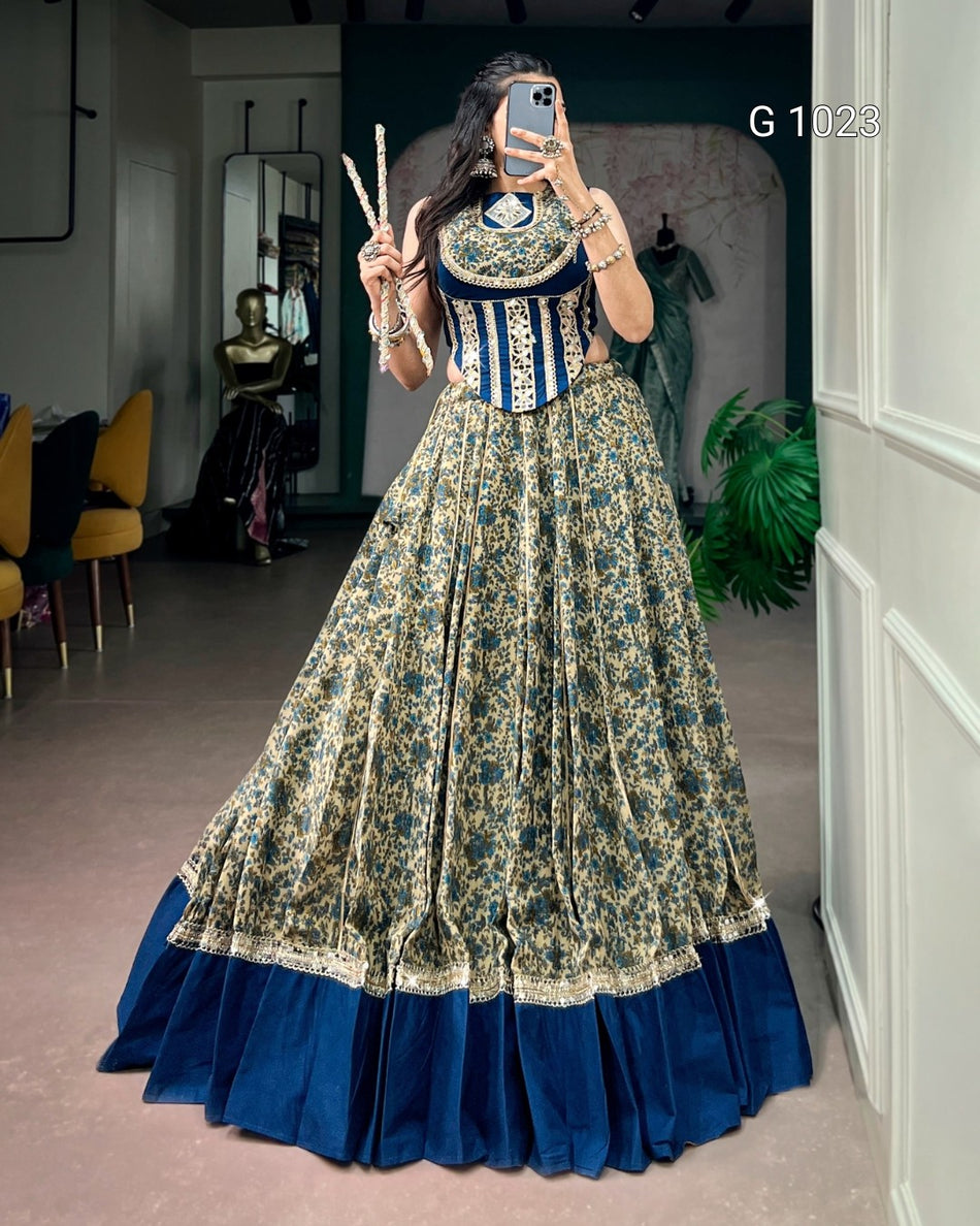 A woman takes a mirror selfie wearing a traditional Indian lehenga choli outfit. The outfit features a navy blue choli with gold embroidery and a matching navy blue border, paired with a voluminous skirt in a beige and navy blue floral pattern with a solid navy blue bottom ruffle.