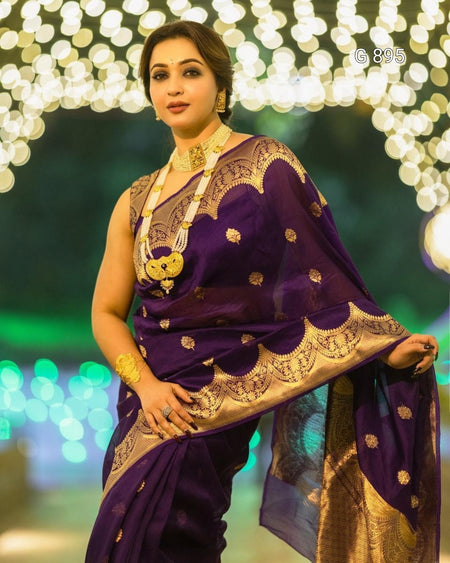 Woman in a traditional purple saree with gold patterns against a festive background