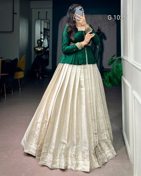 A woman takes a mirror selfie in a boutique wearing a traditional Indian outfit consisting of a dark green long-sleeve top and a voluminous cream-colored pleated skirt with gold zari embroidery. The text 'G 1025' is visible in the top right corner.