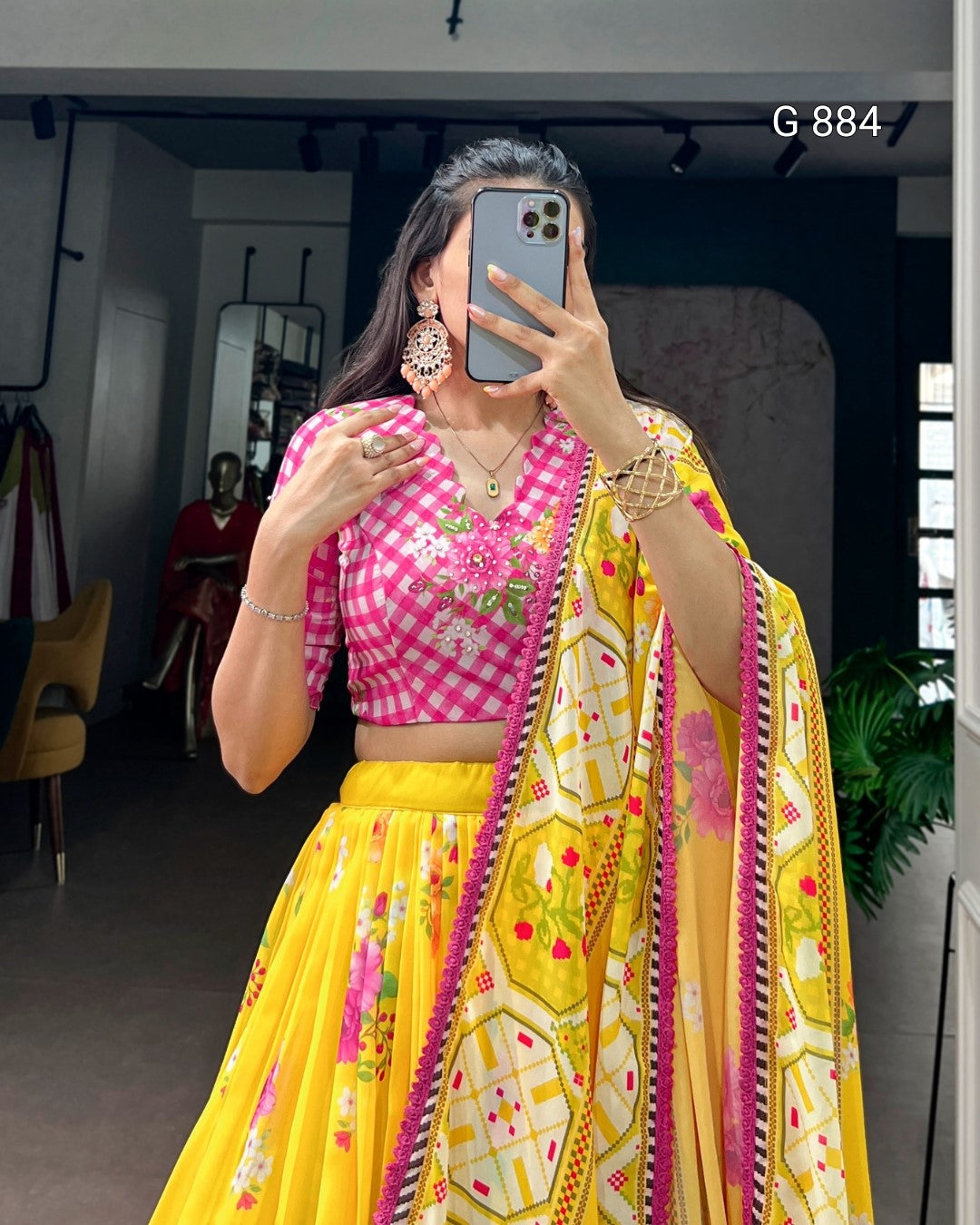 Person wearing a pink and yellow traditional outfit with a patterned dupatta, taking a mirror selfie.