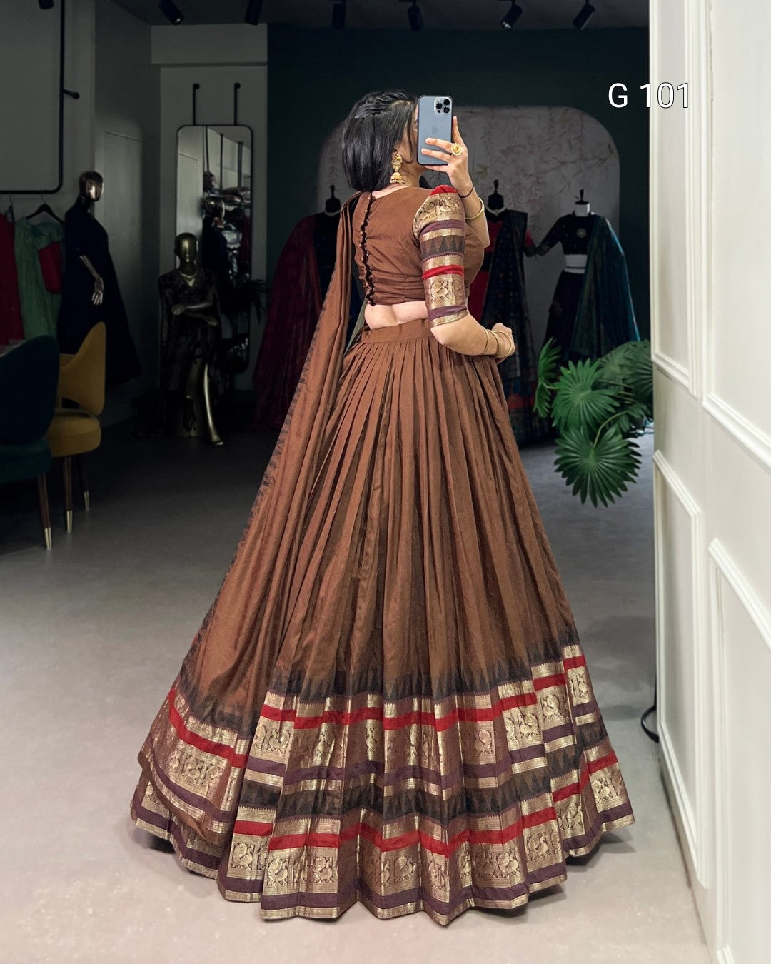 Person wearing a long brown dress with red and gold patterns in a clothing store.