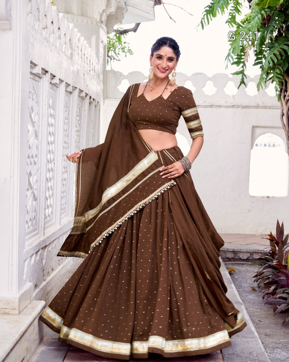 Woman wearing a traditional brown saree with gold accents in an outdoor setting.