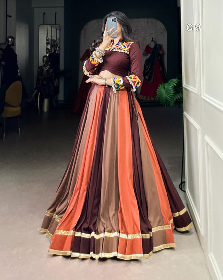 Person wearing a long, multicolored dress with floral accessories in a room.