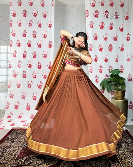 Woman in a traditional brown and gold outfit standing in front of a white curtain with red handprints.