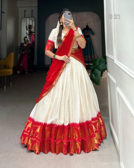 Person wearing a red and white saree in a room with a mirror and chair.