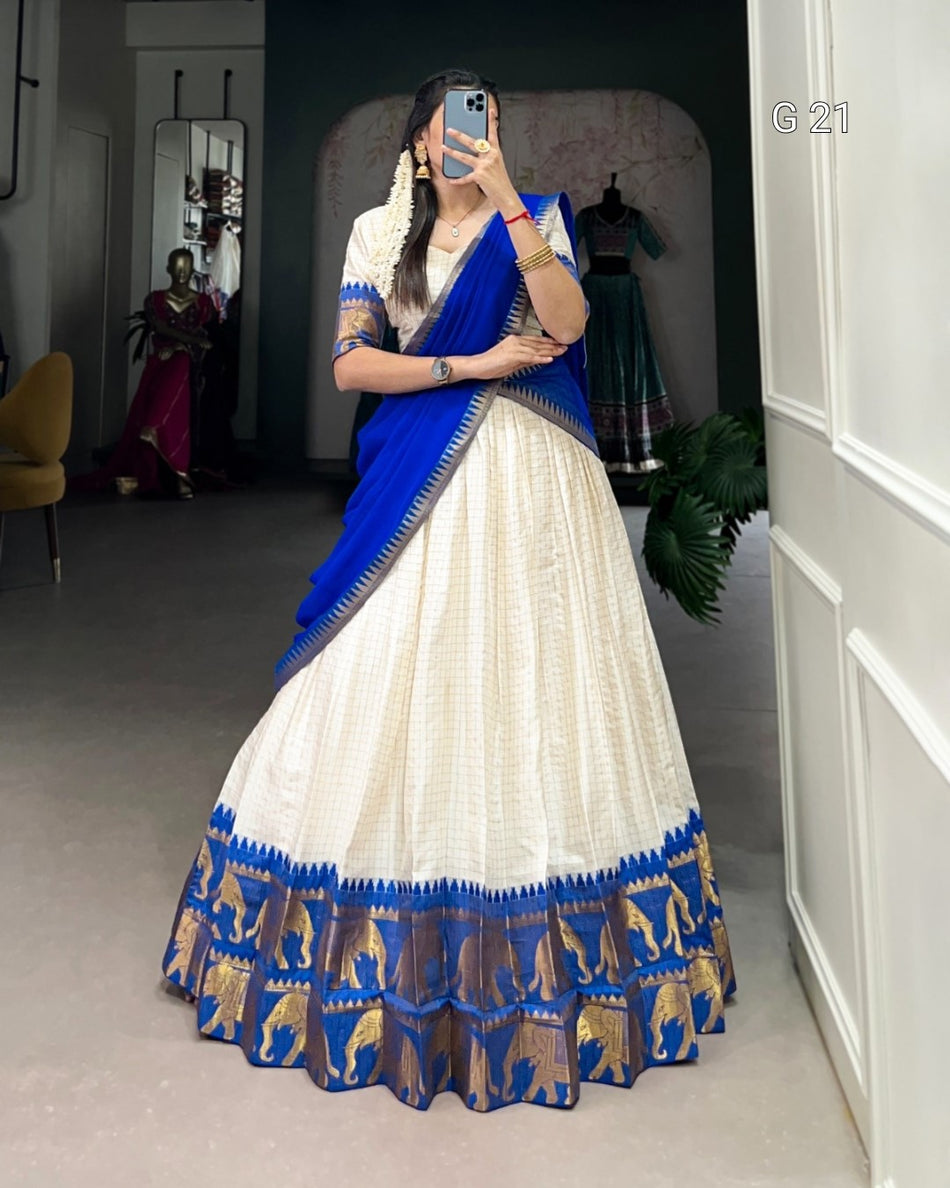 Woman wearing a blue and white saree with elephant patterns in a room.