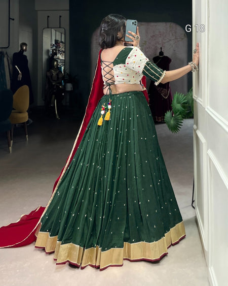 Woman taking a mirror selfie wearing a green and red traditional outfit.