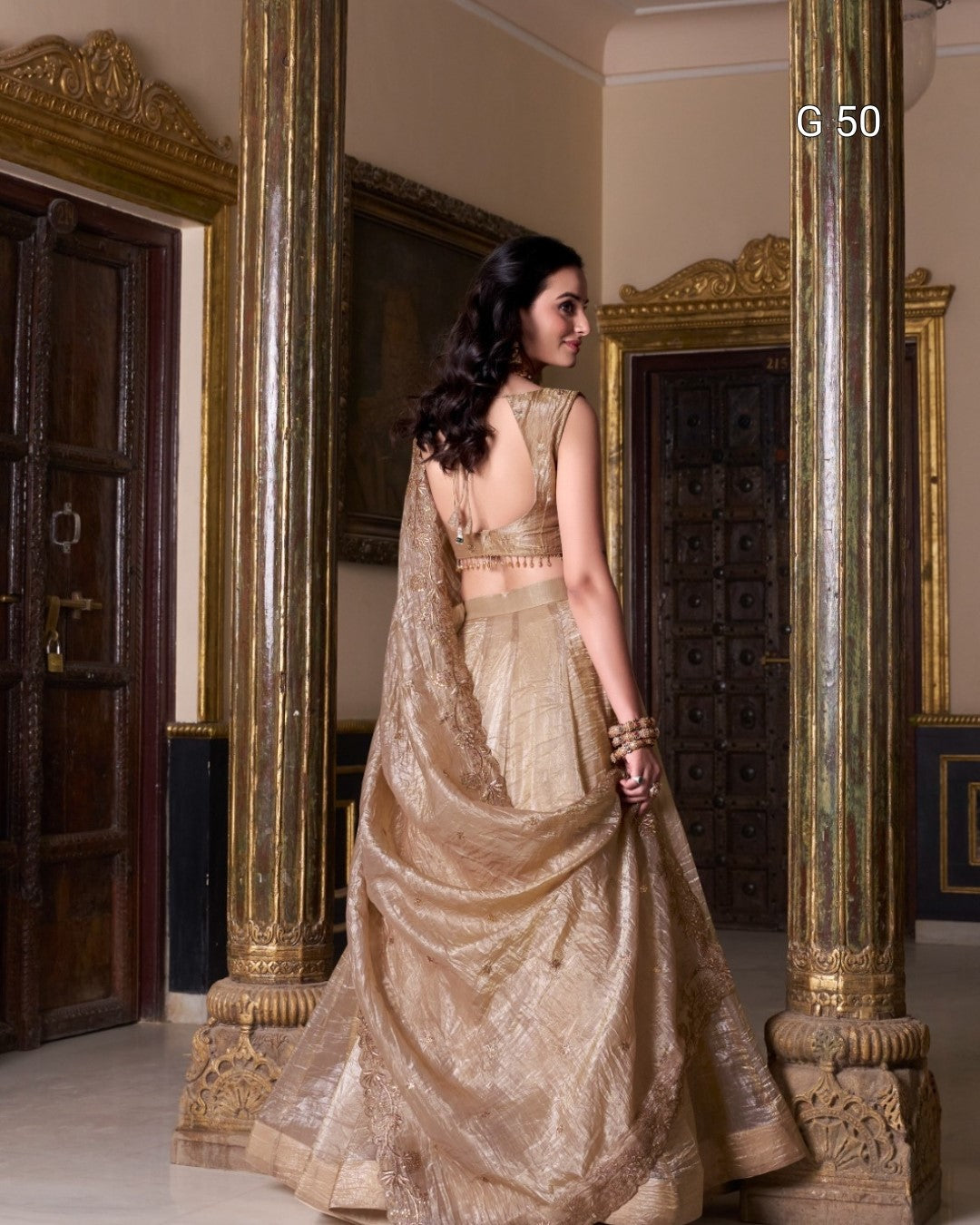 Woman in a gold traditional outfit standing in an ornate room with columns.