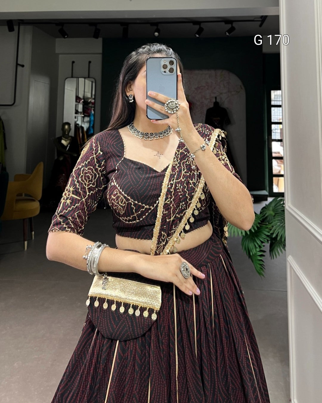 Person wearing a traditional outfit with a matching handbag in an indoor setting.