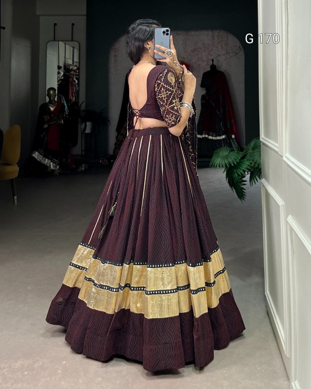 Woman taking a mirror selfie wearing a traditional outfit with a dark purple and gold dress.