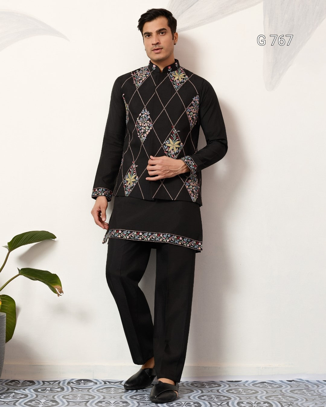 Man wearing a black embroidered traditional outfit with a white background