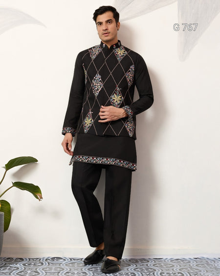 Man wearing a black embroidered traditional outfit with a white background