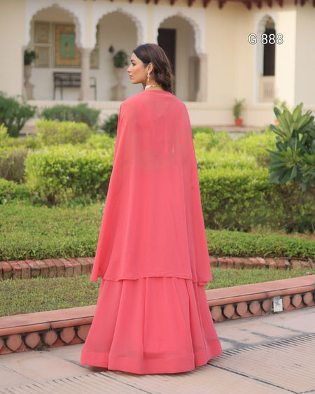 Woman in a pink traditional outfit standing in a garden with a building in the background
