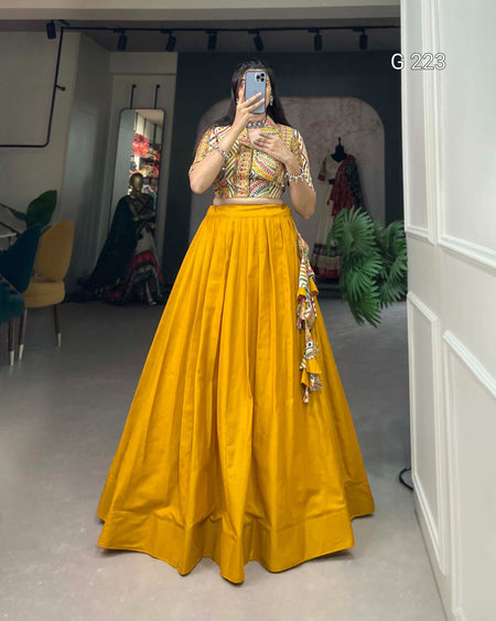 Person wearing a traditional outfit with a yellow skirt and patterned top in a room.