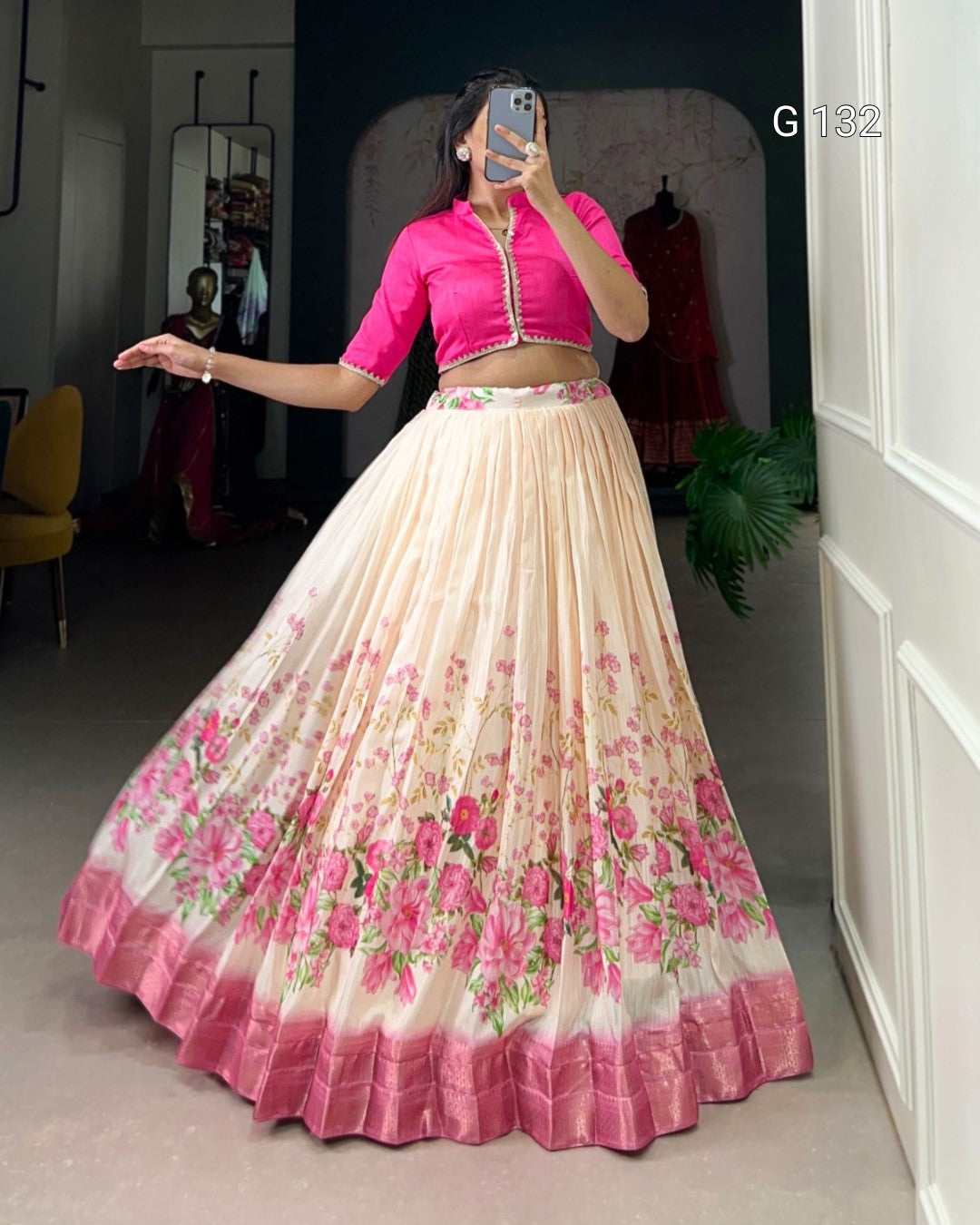 Woman wearing a pink blouse and floral skirt in a room.