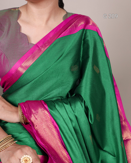 Green saree with pink border worn by a person, on a neutral background