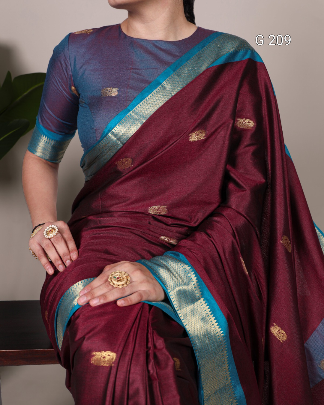 Maroon saree with blue border worn by a person, against a neutral background