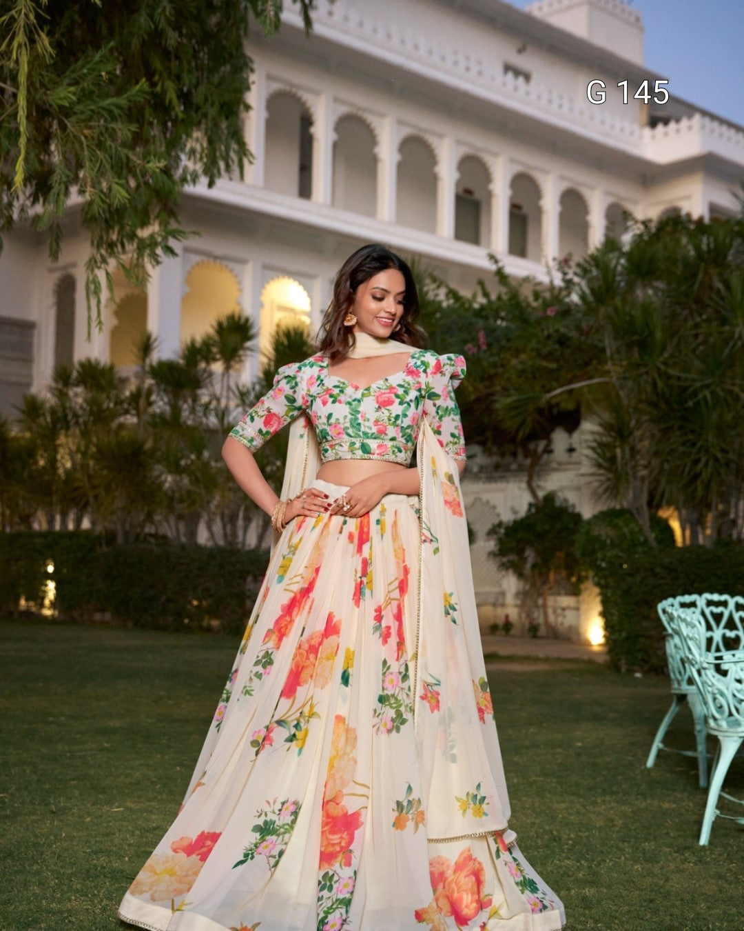 Woman in a floral outfit standing in front of a building with greenery
