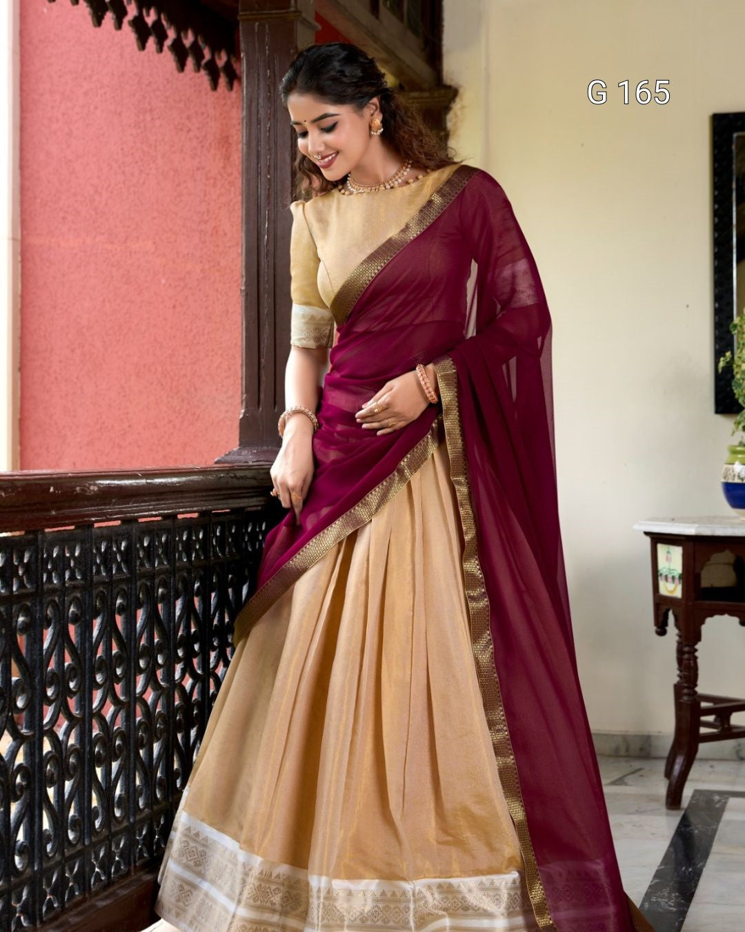 Woman wearing a maroon and beige saree in an indoor setting