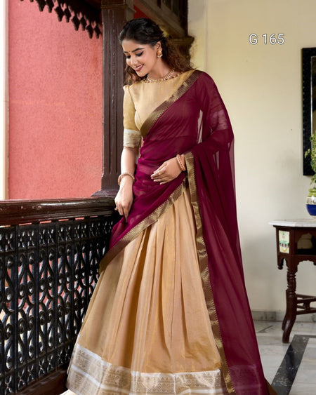 Woman wearing a maroon and beige saree in an indoor setting