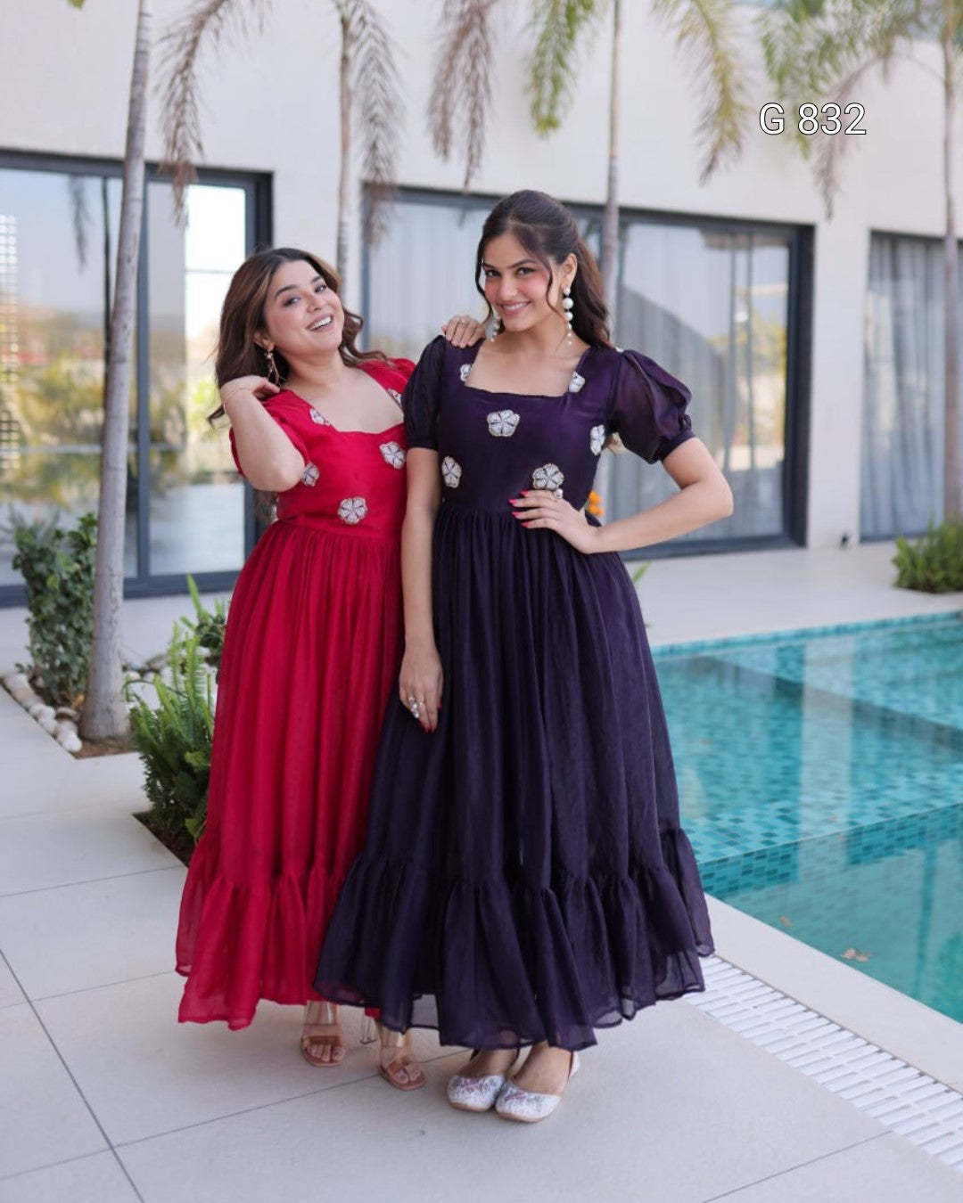Two women in formal dresses standing by a poolside.