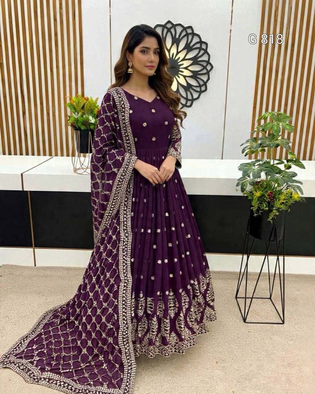 Woman in a purple traditional outfit with intricate designs in an indoor setting.