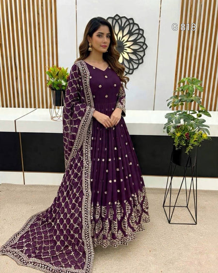 Woman in a purple traditional outfit with intricate designs in an indoor setting.