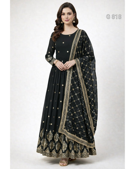 A woman modeling a black floor-length Anarkali gown with gold embroidery and a matching printed dupatta, shown against a plain light gray studio background.