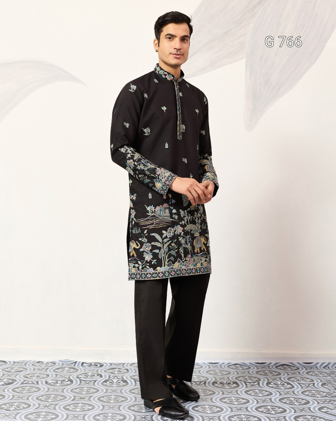 Man wearing a black embroidered kurta with pants on a white background