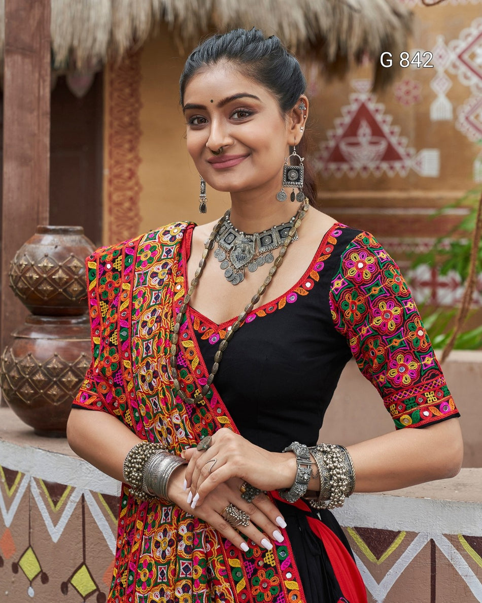 Woman in traditional attire with colorful patterns and jewelry in a decorative setting.