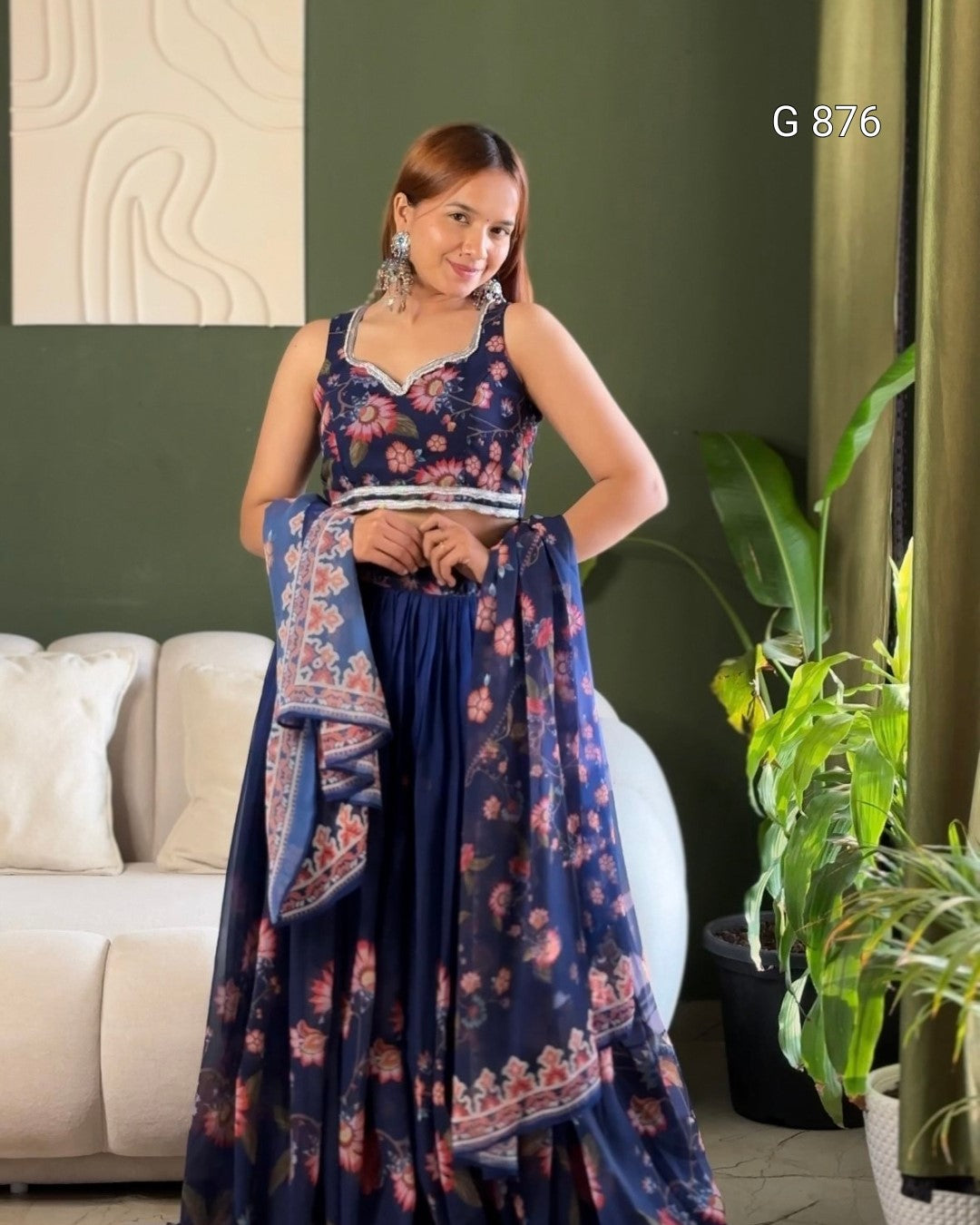 Woman in a floral dress standing in a living room with a plant and sofa.