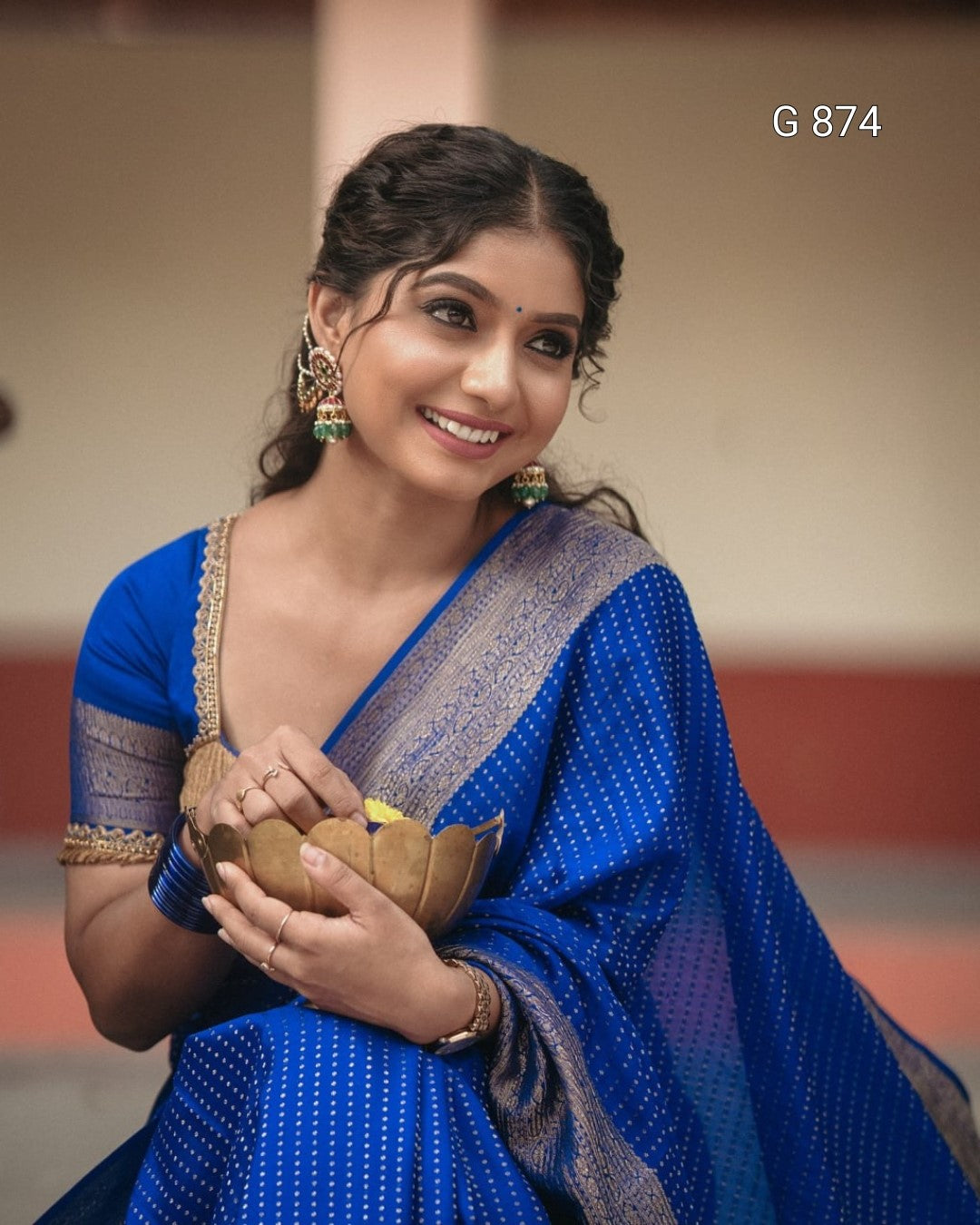 Woman in a blue saree holding a bowl with a blurred background
