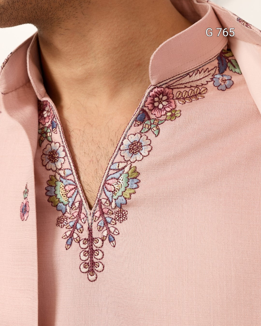 Close-up of a pink blouse with floral embroidery on a plain background
