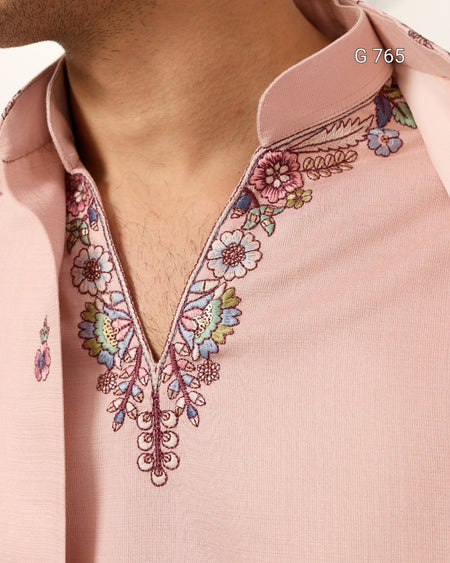 Close-up of a pink blouse with floral embroidery on a plain background