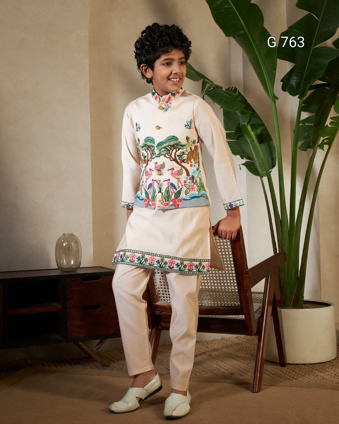 Child wearing a traditional outfit with floral embroidery in a room setting.