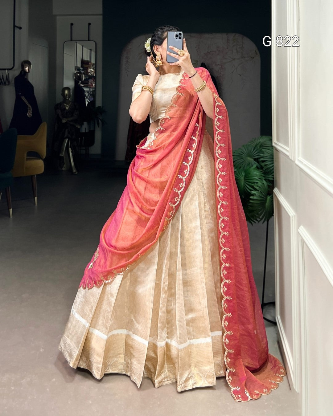 Person wearing a traditional outfit with a pink and gold saree in an indoor setting.