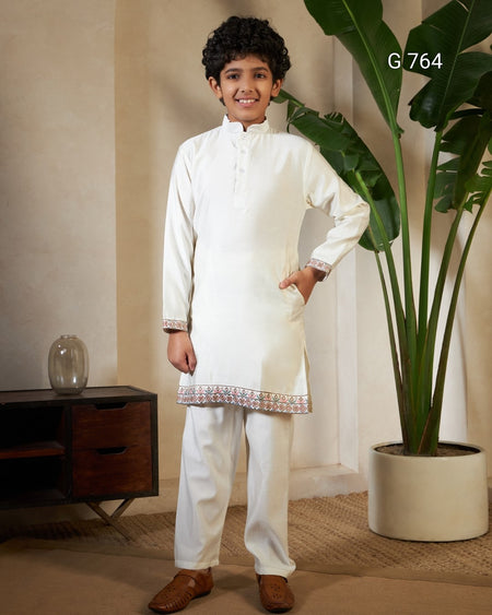 Child wearing a traditional outfit standing in a room with a plant and furniture.