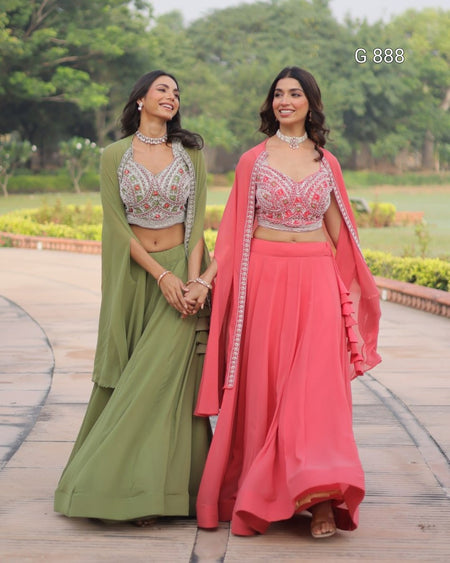 Two women in traditional outfits standing outdoors with greenery in the background