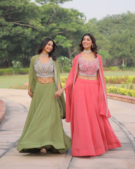Two women in traditional outfits standing outdoors with greenery in the background