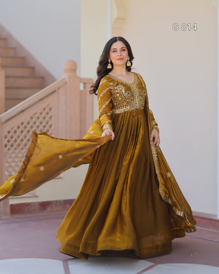 Woman in a mustard yellow traditional outfit with gold embroidery in an indoor setting.
