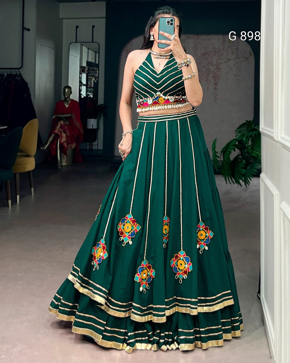 Woman wearing a green embroidered traditional outfit in a room.