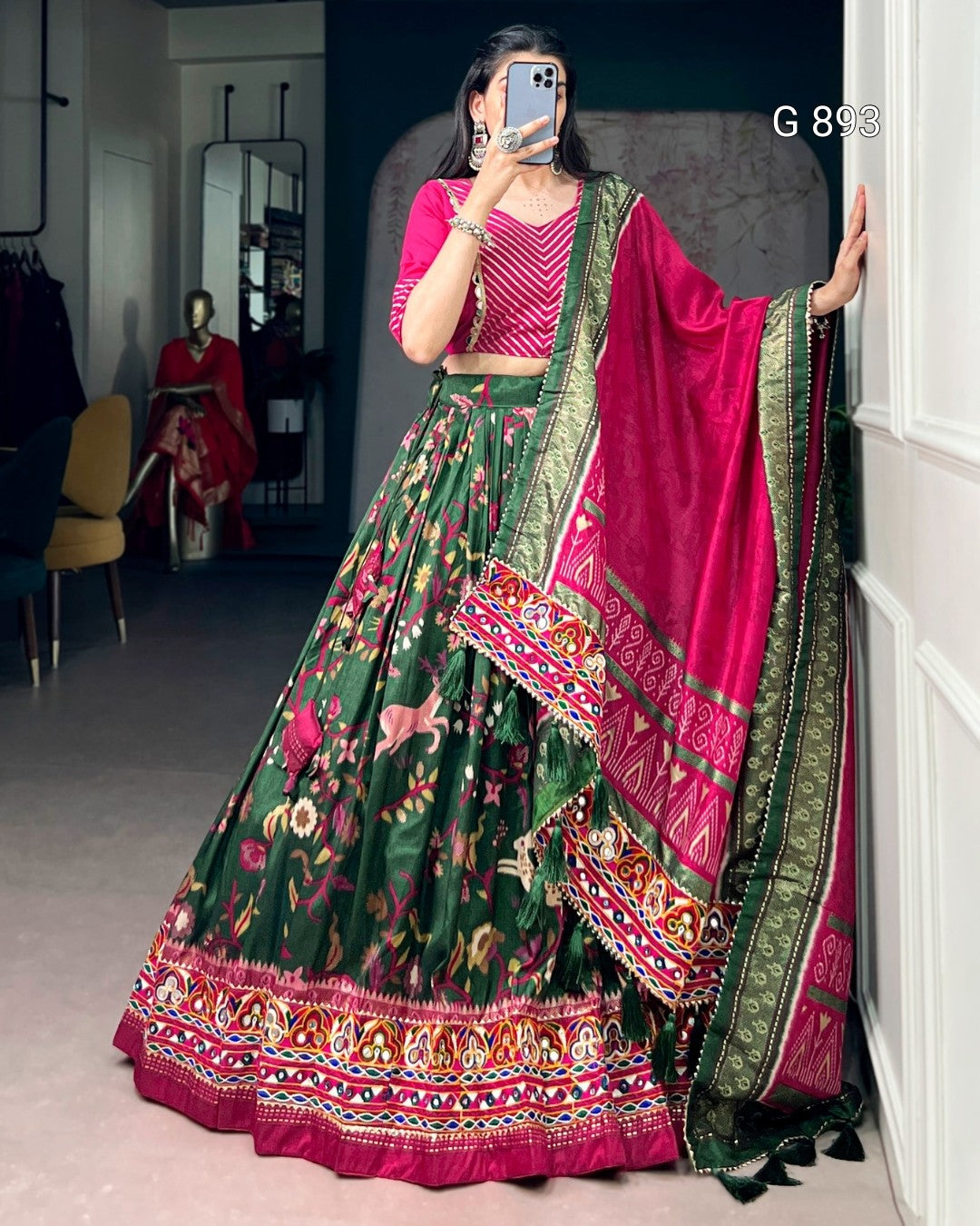 Woman wearing a traditional green and pink lehenga with a mirror reflection in the background.
