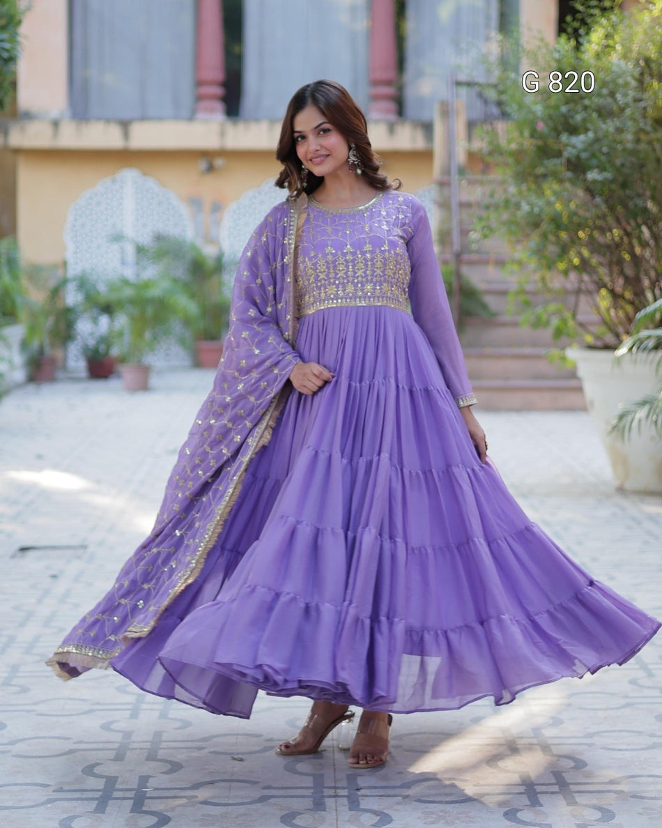 Woman wearing a purple traditional outfit with gold embroidery outdoors.